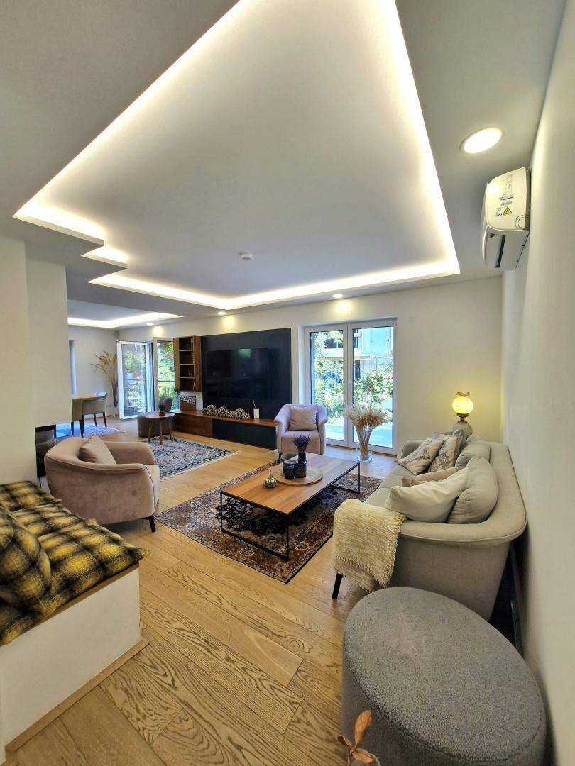 Gemütliches Wohnzimmer mit Sofa, Couchtisch und Klimaanlage, hell und modern eingerichtet mit Holzboden.