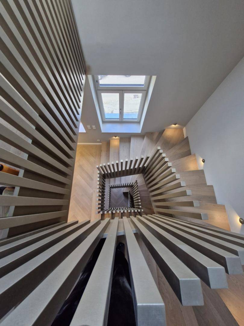 Beeindruckendes Treppenhaus mit modernem Design, Holzstufen und Oberlicht für natürliches Licht.