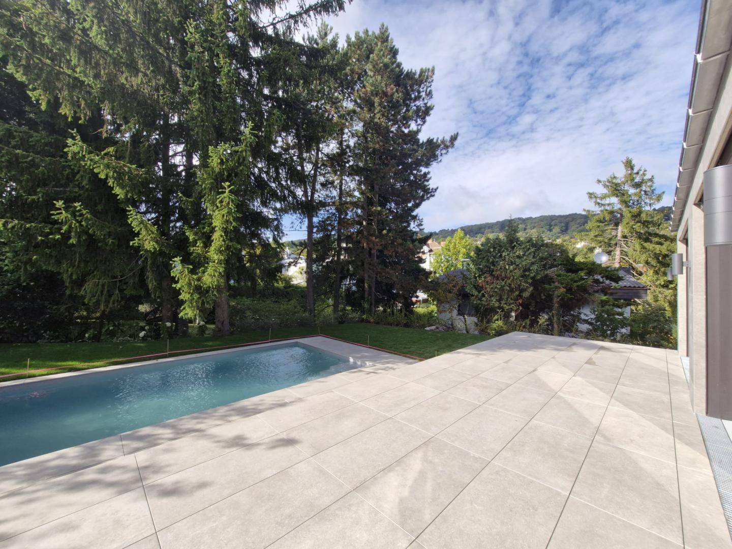 Großer Poolbereich mit weitläufiger Terrasse und Blick auf die grüne Landschaft und die Umgebung.