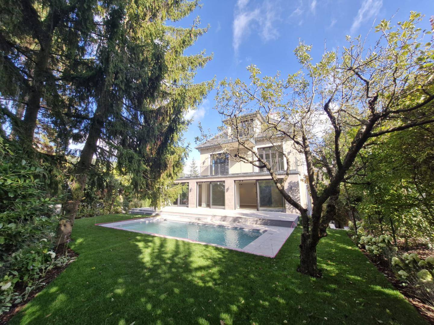 Großzügiger Gartenbereich mit Swimmingpool und altem Baumbestand umgeben von viel Grün.