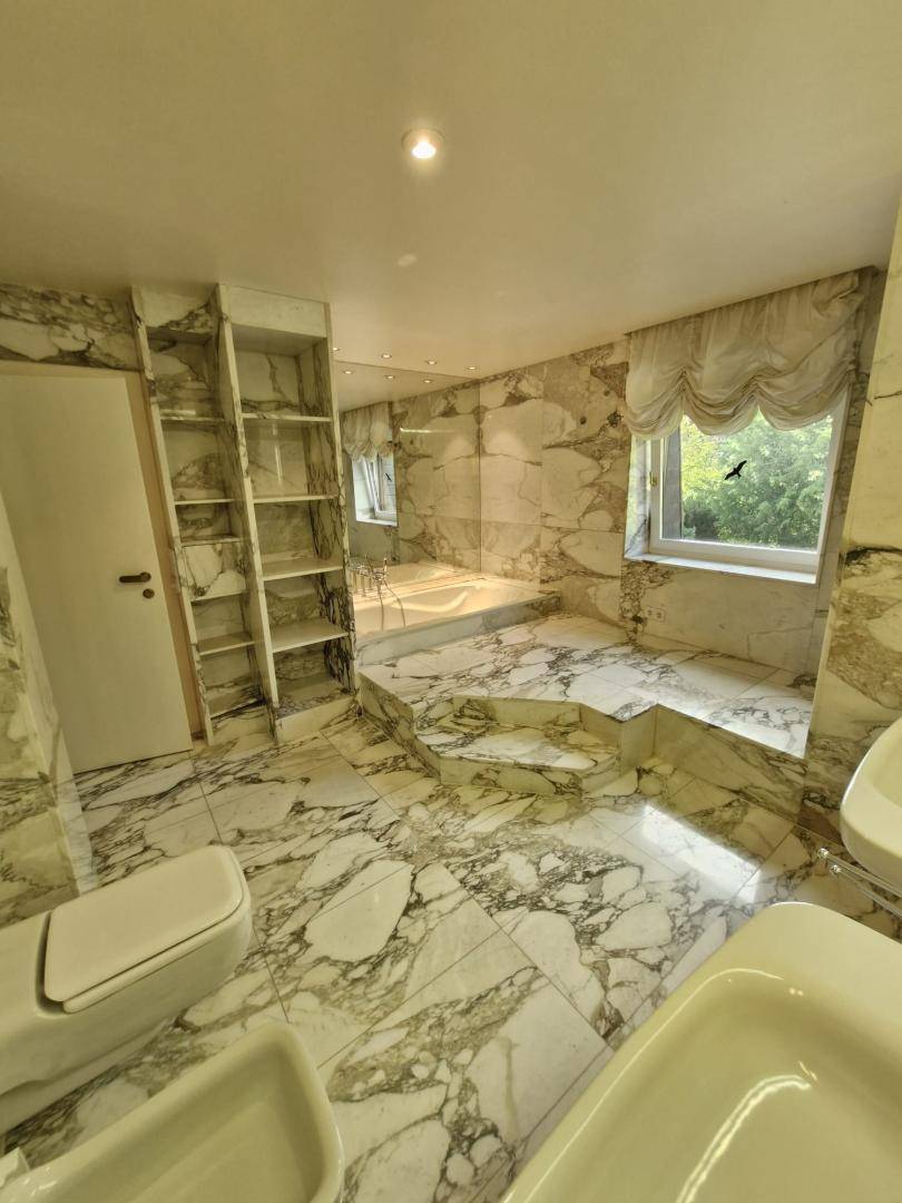 Elegantes Badezimmer mit Marmorfliesen an Wänden und Boden, inklusive Badewanne und Bidet.