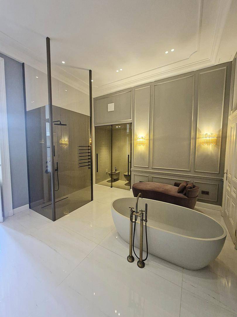 Luxuriöses Badezimmer mit freistehender Badewanne, großer Dusche und eleganten Armaturen.