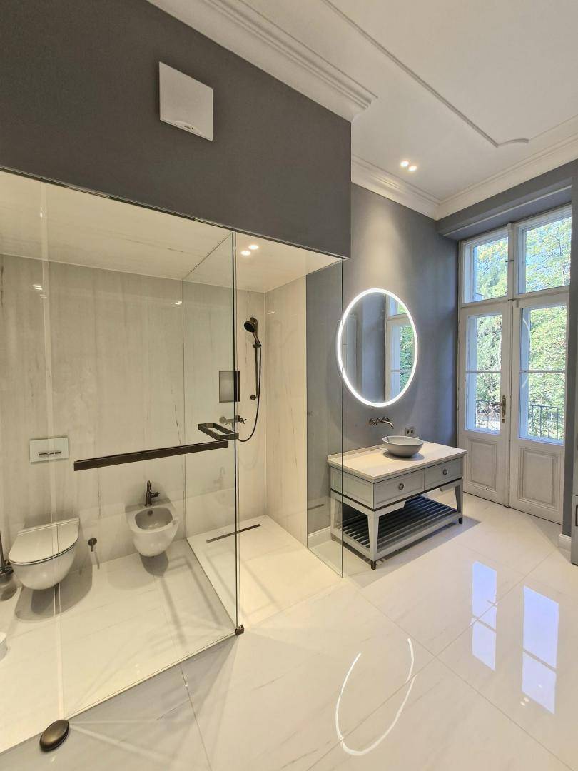Modernes Badezimmer mit begehbarer Dusche, Bidet und großem Fenster.