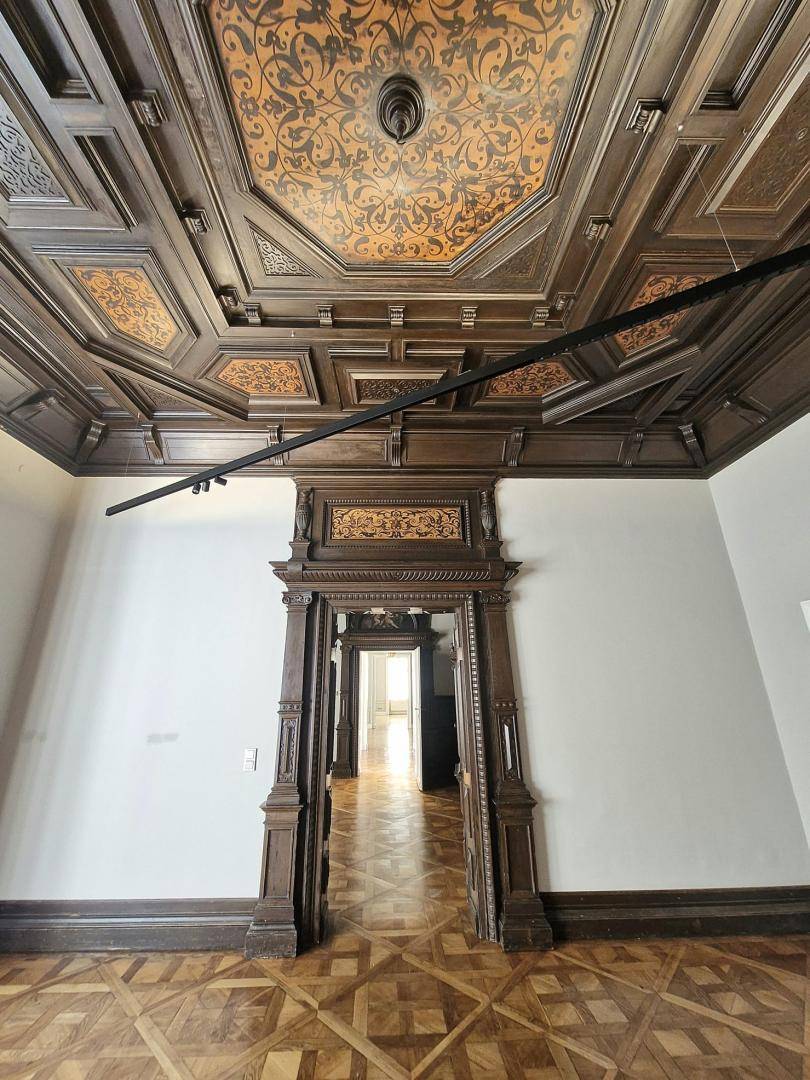 Prunkvoller Raum mit Kassettendecke, Holztäfelung und Fischgrätparkett.