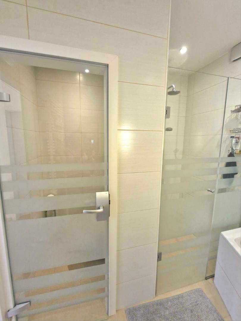 Duschbereich im modernen Badezimmer mit Glasabtrennung und hellen Fliesen.