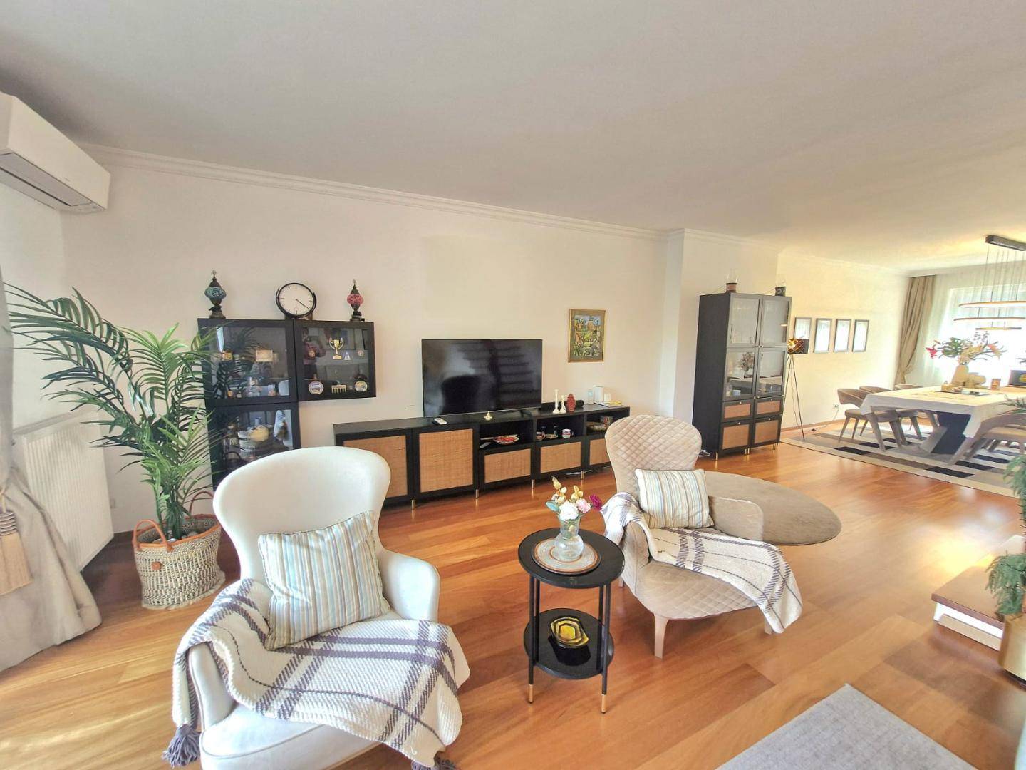 Gemütliches Wohnzimmer mit bequemen Sesseln, Fernseher und Holzboden, offen zum Essbereich.