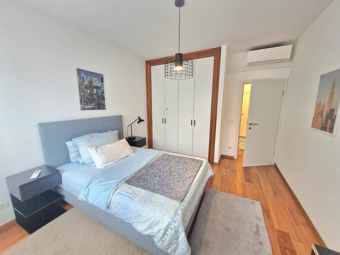 Schlafzimmer mit integriertem Kleiderschrank, Klimaanlage und Holzboden, hell und funktional.