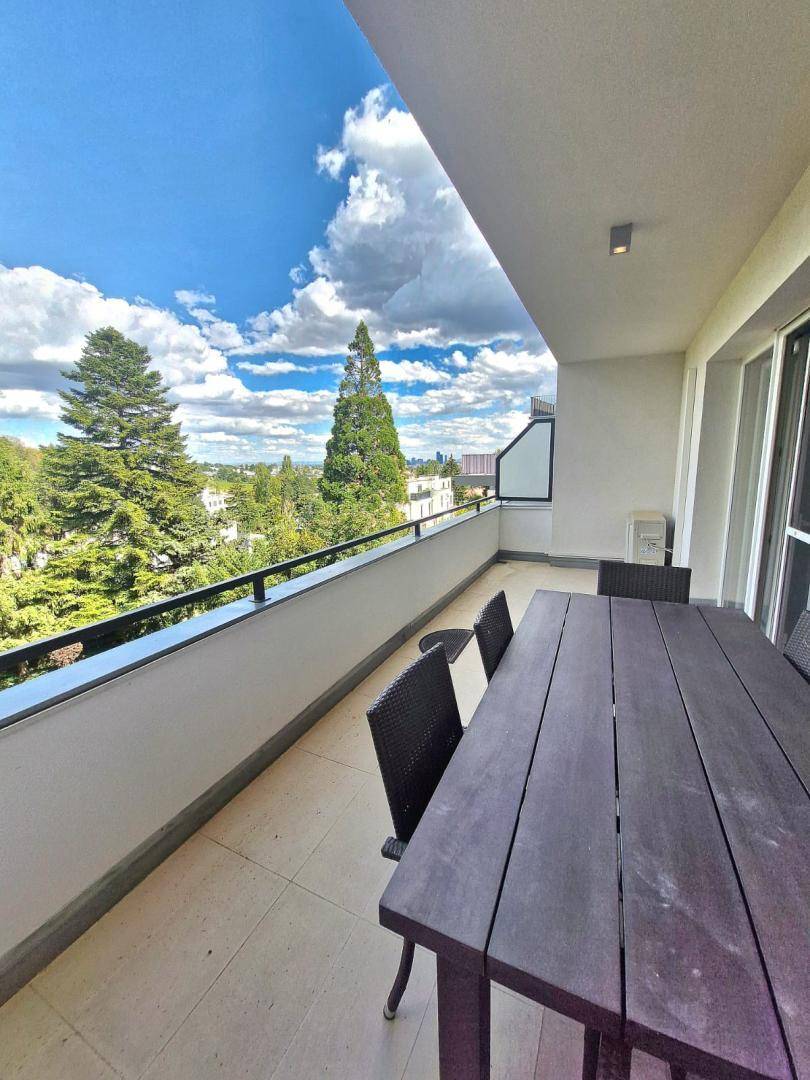 Großer Balkon mit Esstisch und Stühlen, bietet einen weiten Blick ins Grüne.