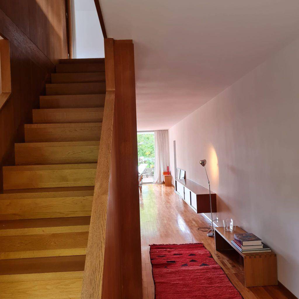 Geräumiger Flur mit Holztreppe und Blick auf den hellen Wohnbereich im Hintergrund.