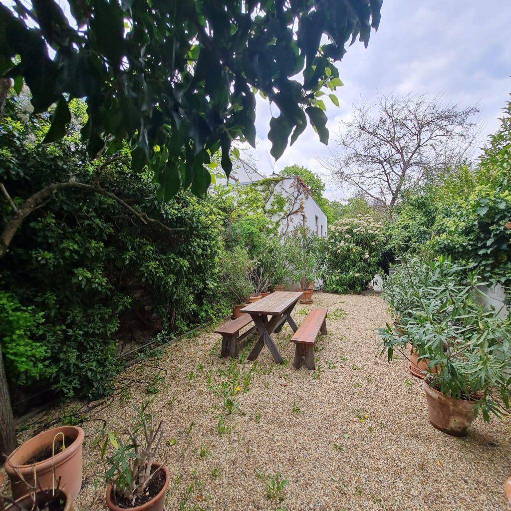 Kiesgarten mit rustikalem Holztisch und Bänken, umgeben von üppiger Vegetation.