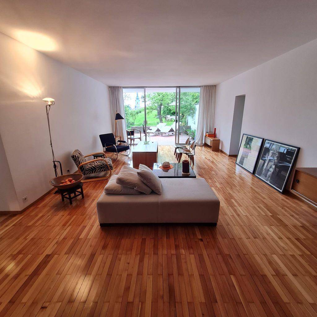 Helles Wohnzimmer mit Holzboden, moderner Einrichtung und großen Schiebetüren zum Garten.