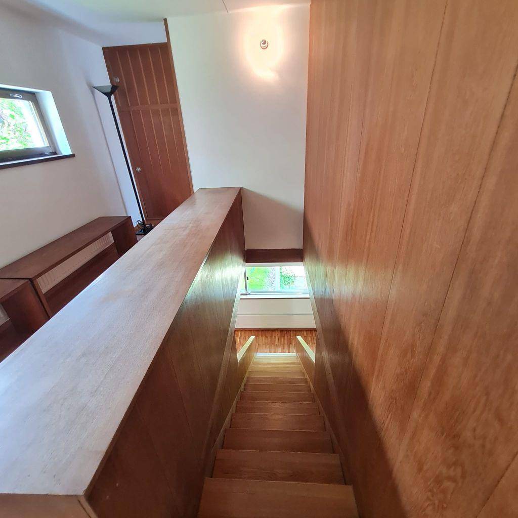 Treppenhaus mit Holzstufen und Geländer, das die verschiedenen Ebenen des Hauses verbindet.