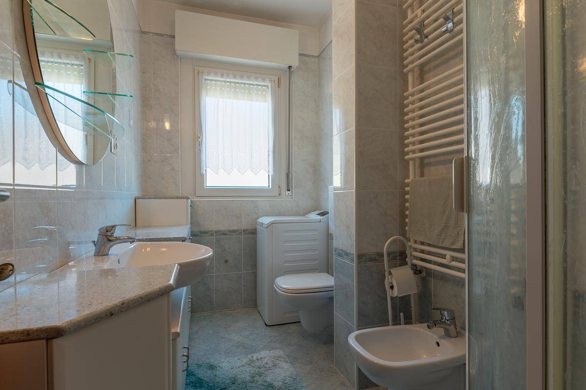 Helles Badezimmer mit Fliesen, Waschmaschine, Bidet und Fenster.
