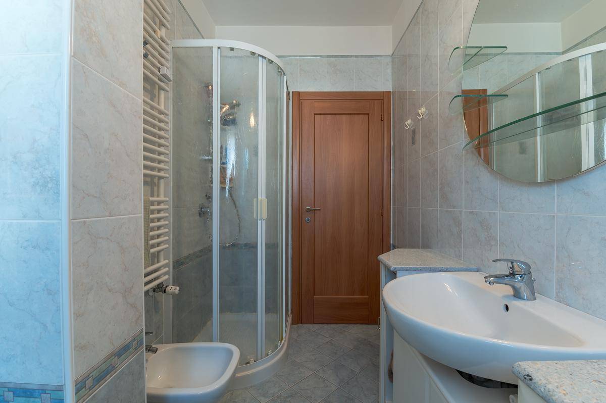Modernes Badezimmer mit Duschkabine, Bidet und großem Spiegel.