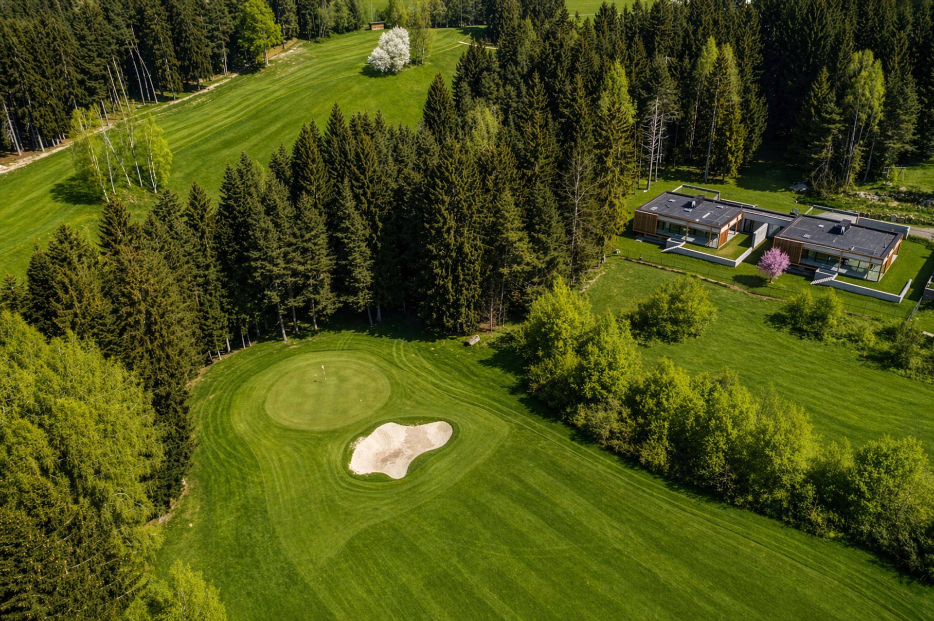Luftaufnahme der modernen Häuser neben einem Golfplatz und umgeben von dichtem Wald.