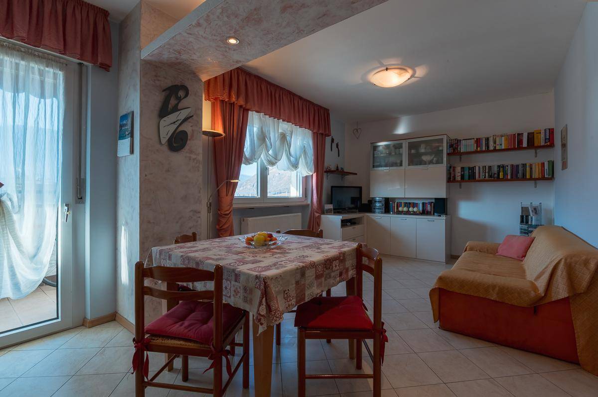 Gemütlicher Wohn-Essbereich mit Fliesenboden, Sofa und Zugang zum Balkon.