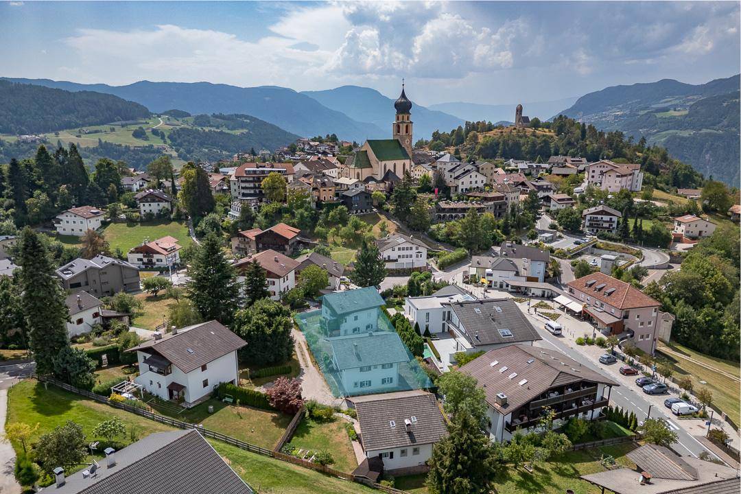 Luftaufnahme eines malerischen Dorfes in den Bergen mit Kirche und umliegender Natur.