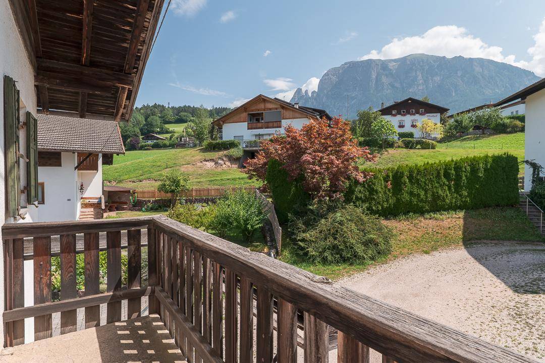 Traditioneller Holzbalkon mit Bergblick und grüner Umgebung, typisch für die Alpenregion.