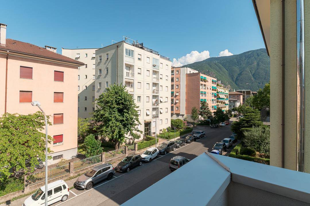 Weitblick vom Balkon über die Stadt und die umliegenden Berge an einem sonnigen Tag.
