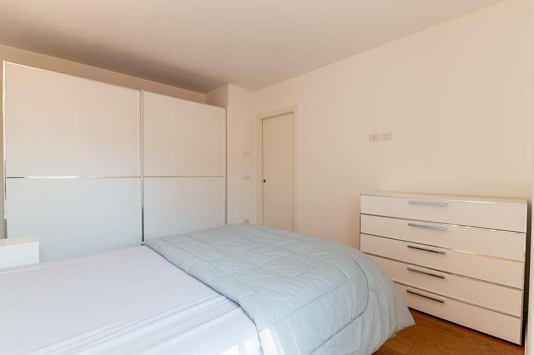 Schlafzimmer mit großem Kleiderschrank, Doppelbett und Holzboden in hellem Ambiente.