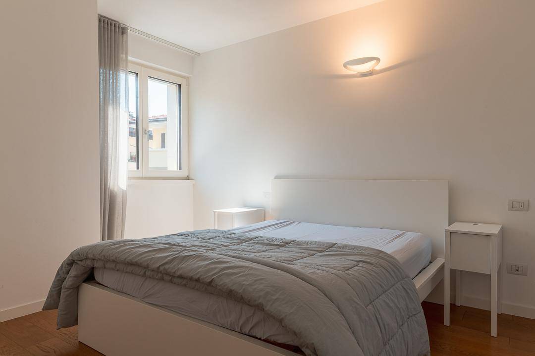 Helles Schlafzimmer mit Doppelbett, Nachttischen und großem Fenster für viel Tageslicht.