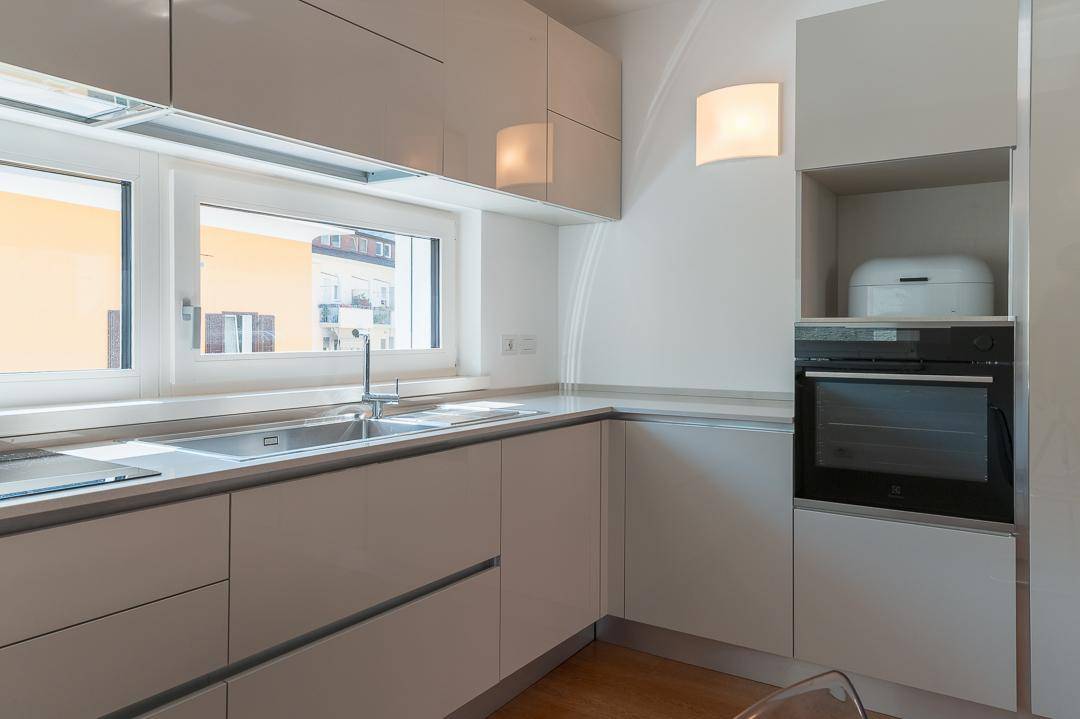 Helle, moderne Küche mit integrierten Geräten, Spüle und viel Arbeitsfläche.