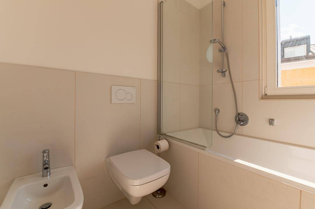 Helles Badezimmer mit Badewanne, Dusche, WC und Bidet in neutralen Farbtönen.