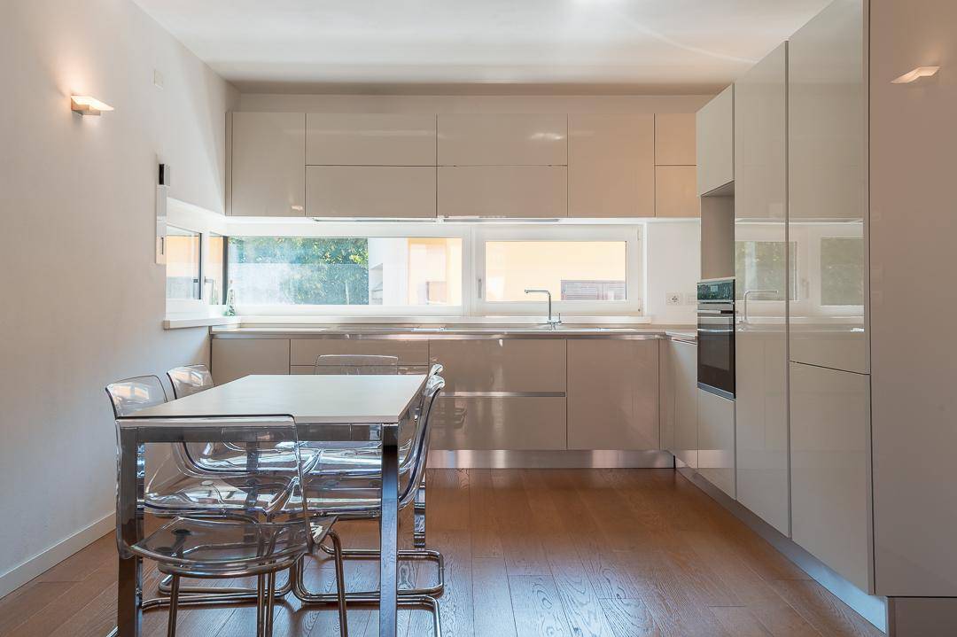 Moderne Einbauküche mit glänzenden Fronten, Essbereich und großen Fenstern.