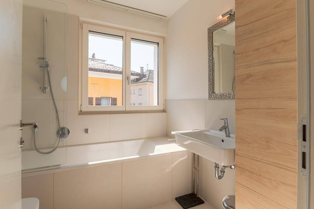 Modernes Badezimmer mit Badewanne, Waschbecken und Fenster für natürliches Licht.