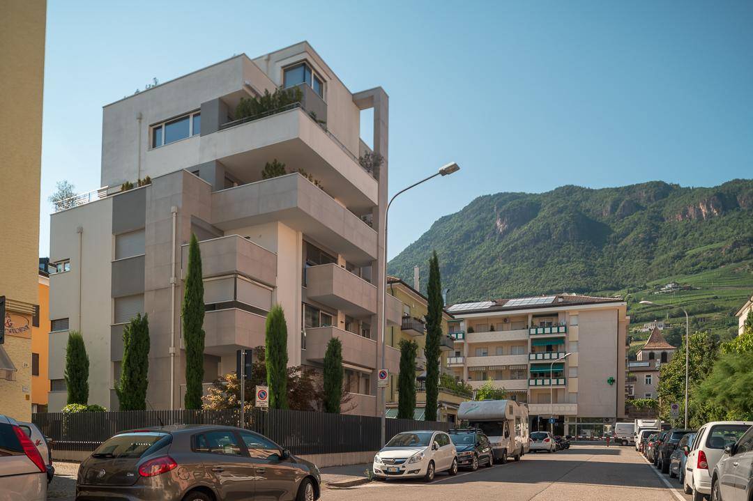 Modernes Mehrfamilienhaus mit Balkonen und Blick auf die umliegende Berglandschaft.