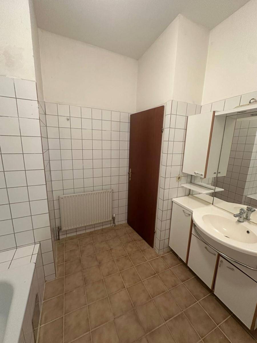 Badezimmer mit Waschbecken, Spiegelschrank und weißen Wandfliesen.