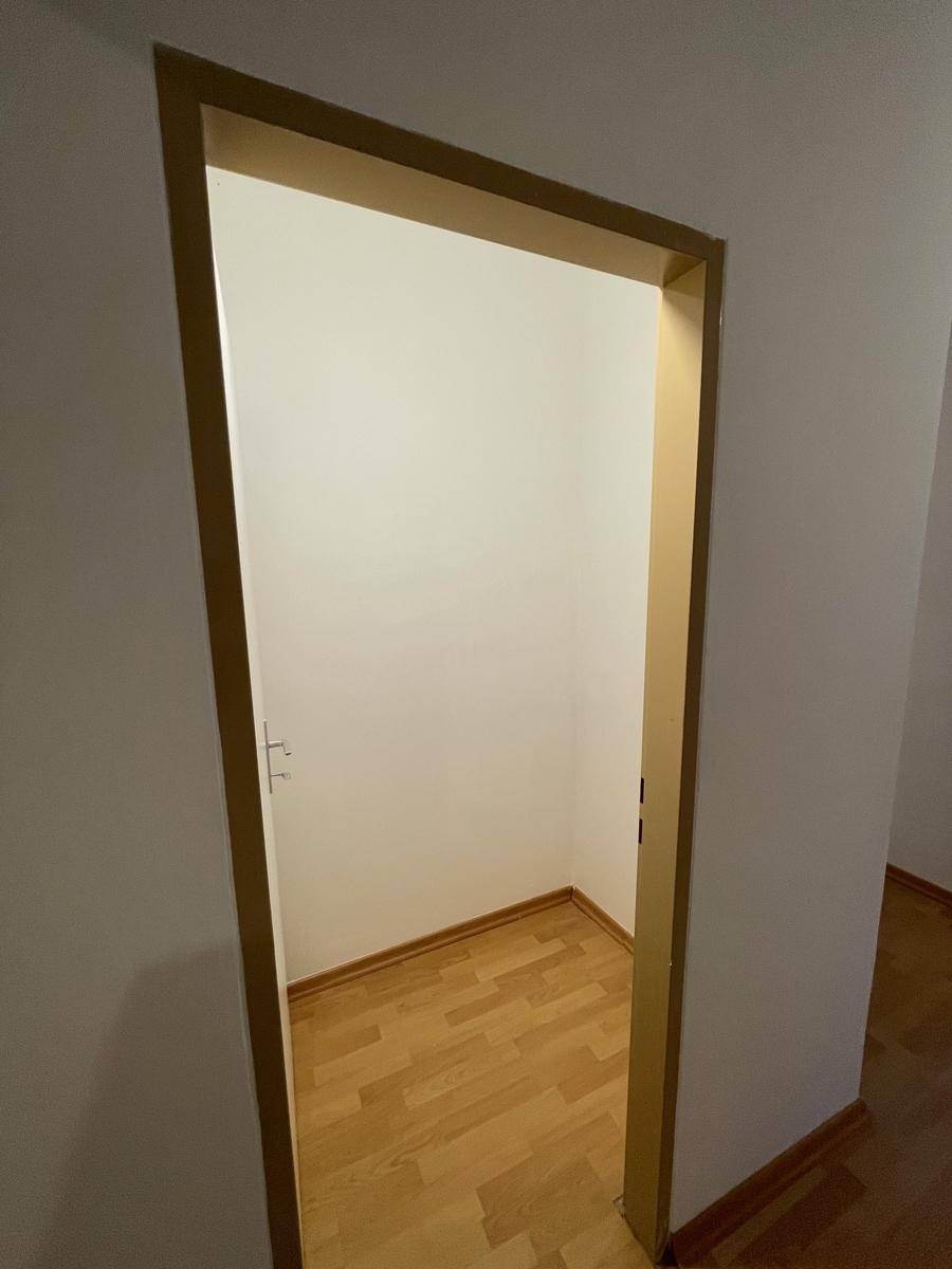Kleiner, leerer Abstellraum mit hellem Parkettboden und weißen Wänden.