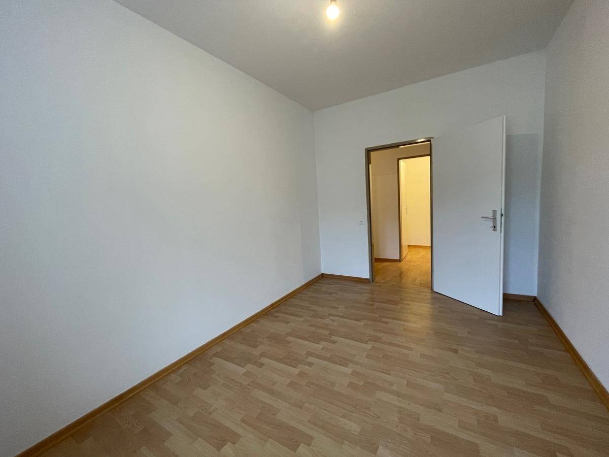 Unmöbliertes Zimmer mit Parkettboden und weiß gestrichenen Wänden, bereit zum Einzug.