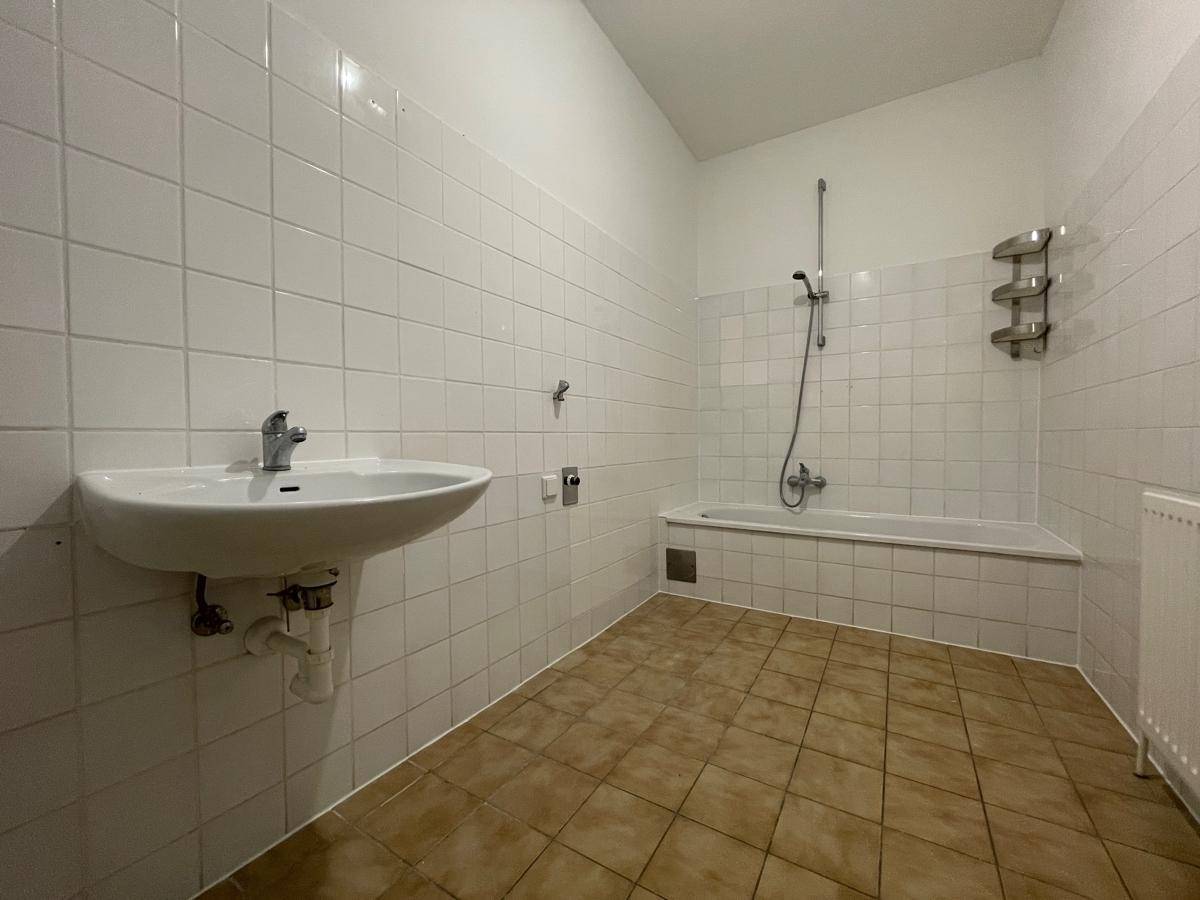 Badezimmer mit Waschbecken, Badewanne und weißen Wandfliesen.