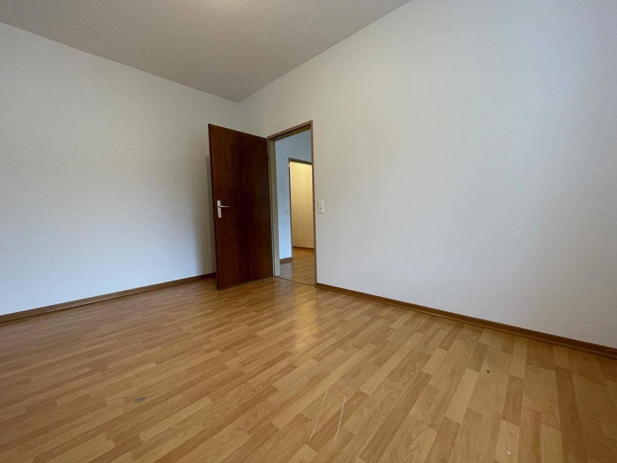 Ruhiges Zimmer mit Parkettboden und weiß gestrichenen Wänden, ideal als Schlaf- oder Arbeitszimmer.