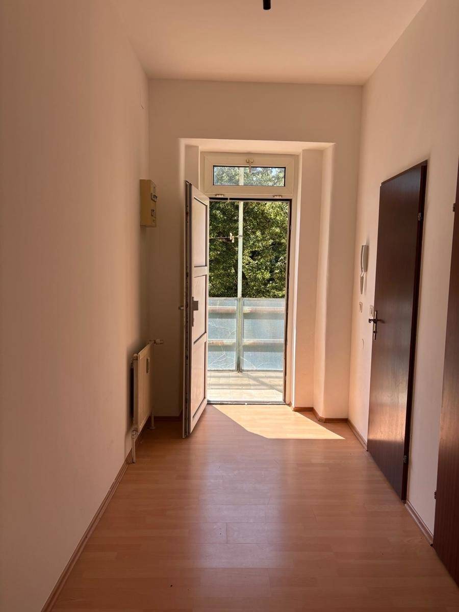 Heller Flur mit Laminatboden und Zugang zu einem Balkon, der viel Tageslicht hereinlässt.