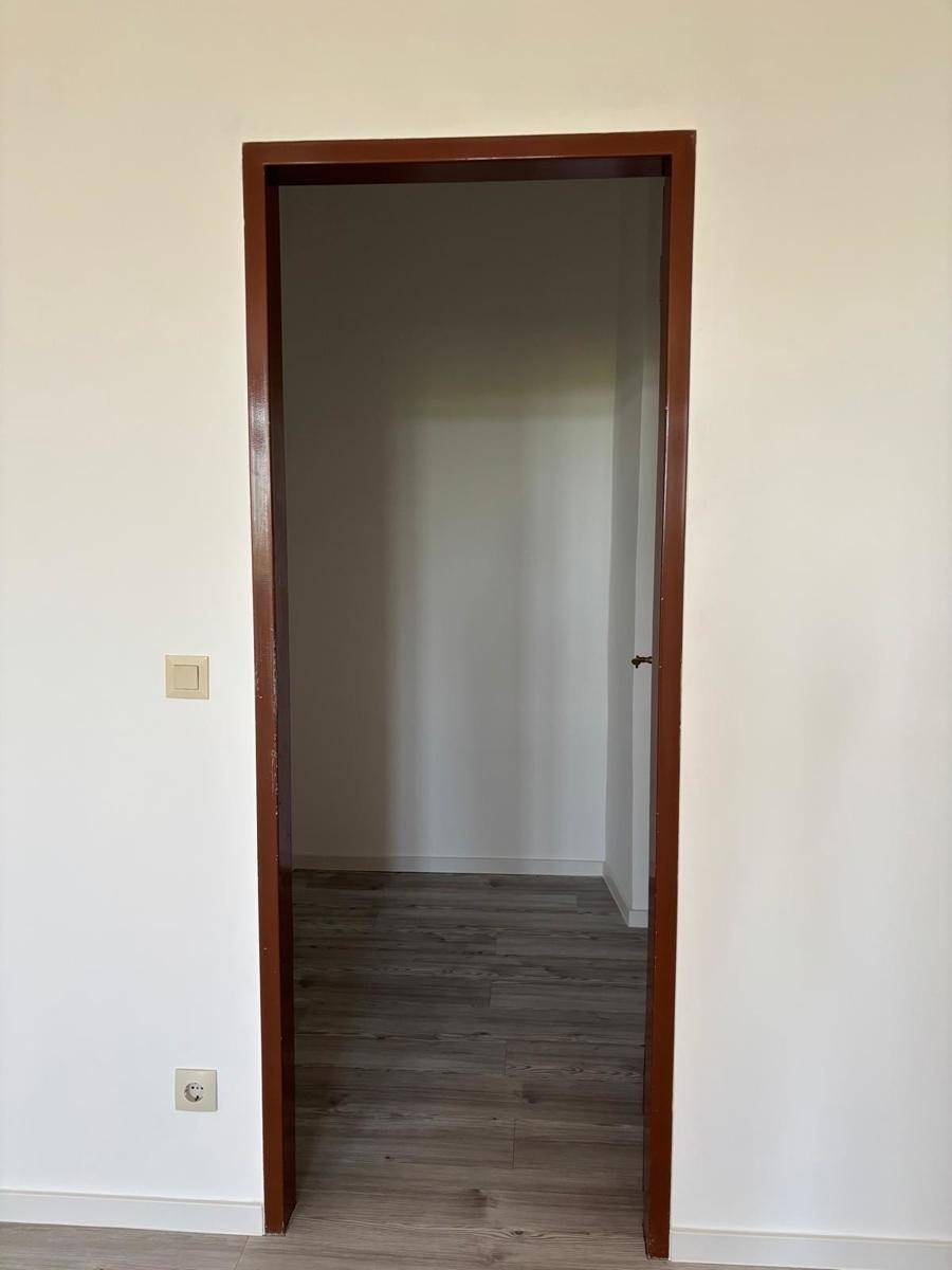 Offener Türrahmen, der den Blick in einen weiteren Raum mit hellem Laminatboden freigibt.