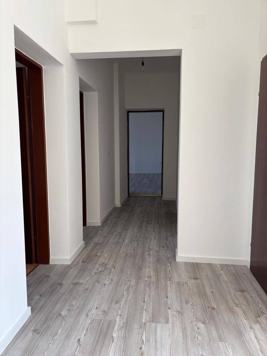 Langer Flur mit hellem Laminatboden und mehreren Türen, die zu verschiedenen Räumen führen.