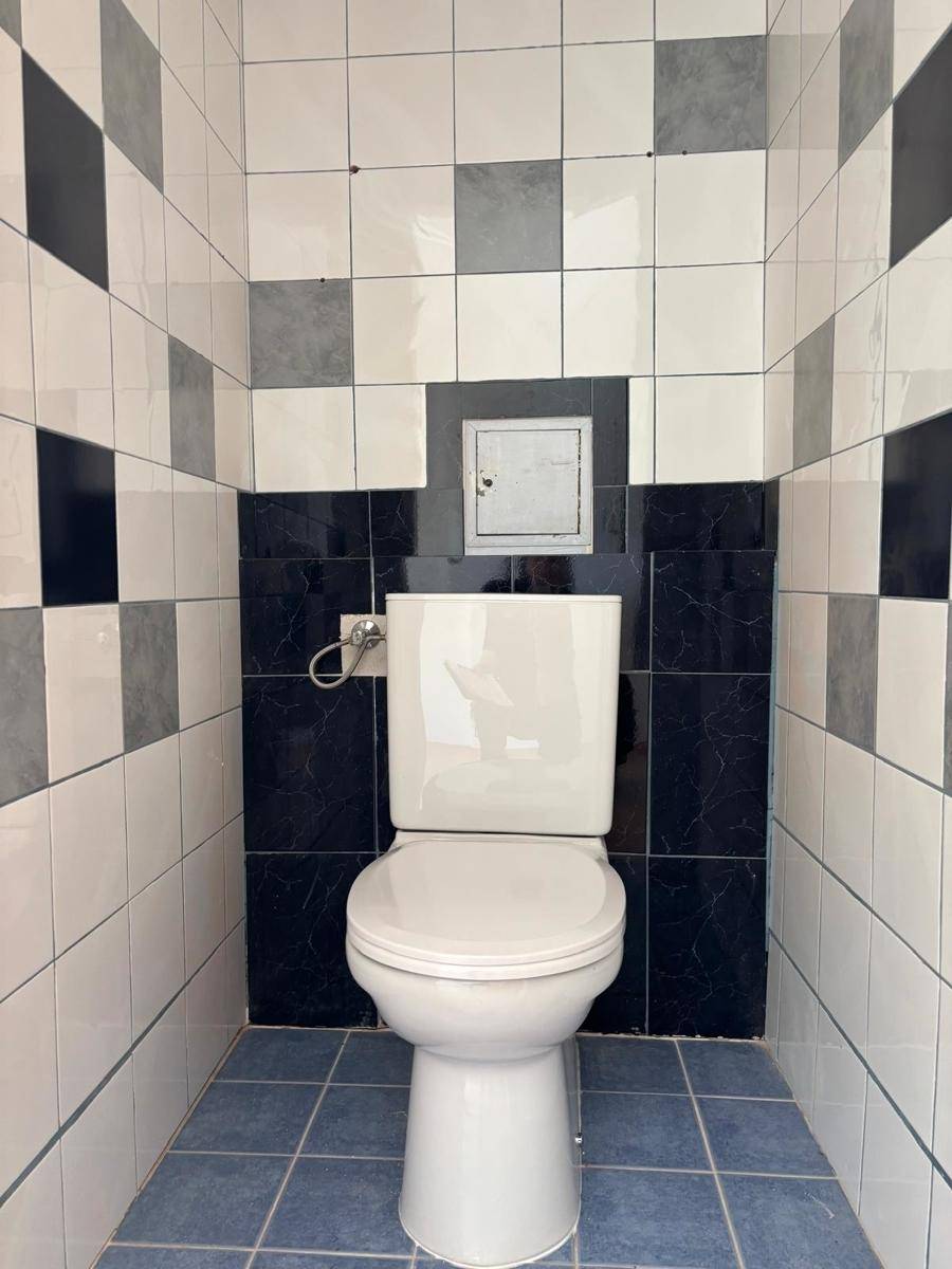 Kleines WC mit auffälligen schwarz-weiß-grau-blauen Fliesen und einer Standardtoilette.