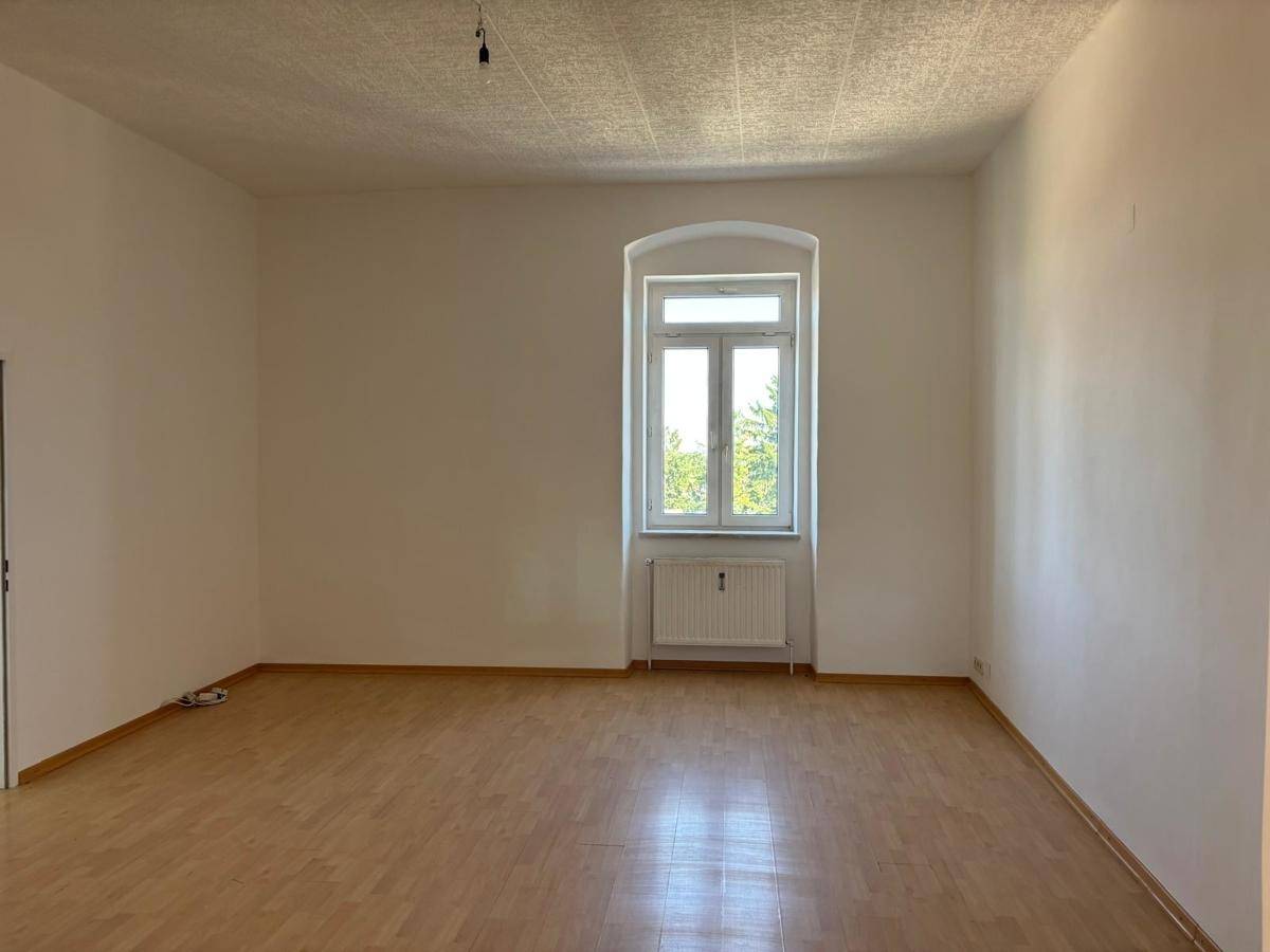 Großes, helles Zimmer mit Laminatboden und weitem Blick ins Grüne, perfekt für einen Wohnbereich.