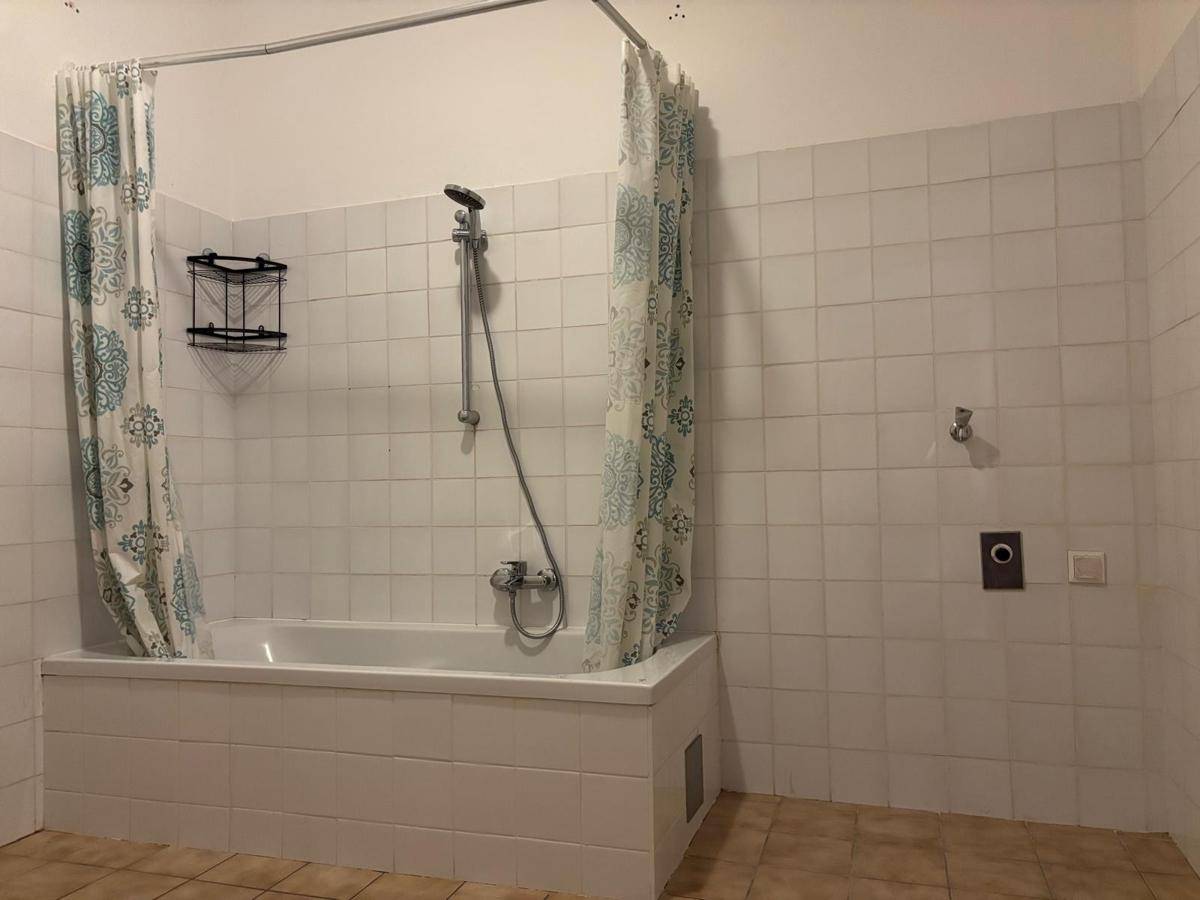 Badezimmer mit Badewanne und Duschvorhang, komplett gefliest und funktional eingerichtet.