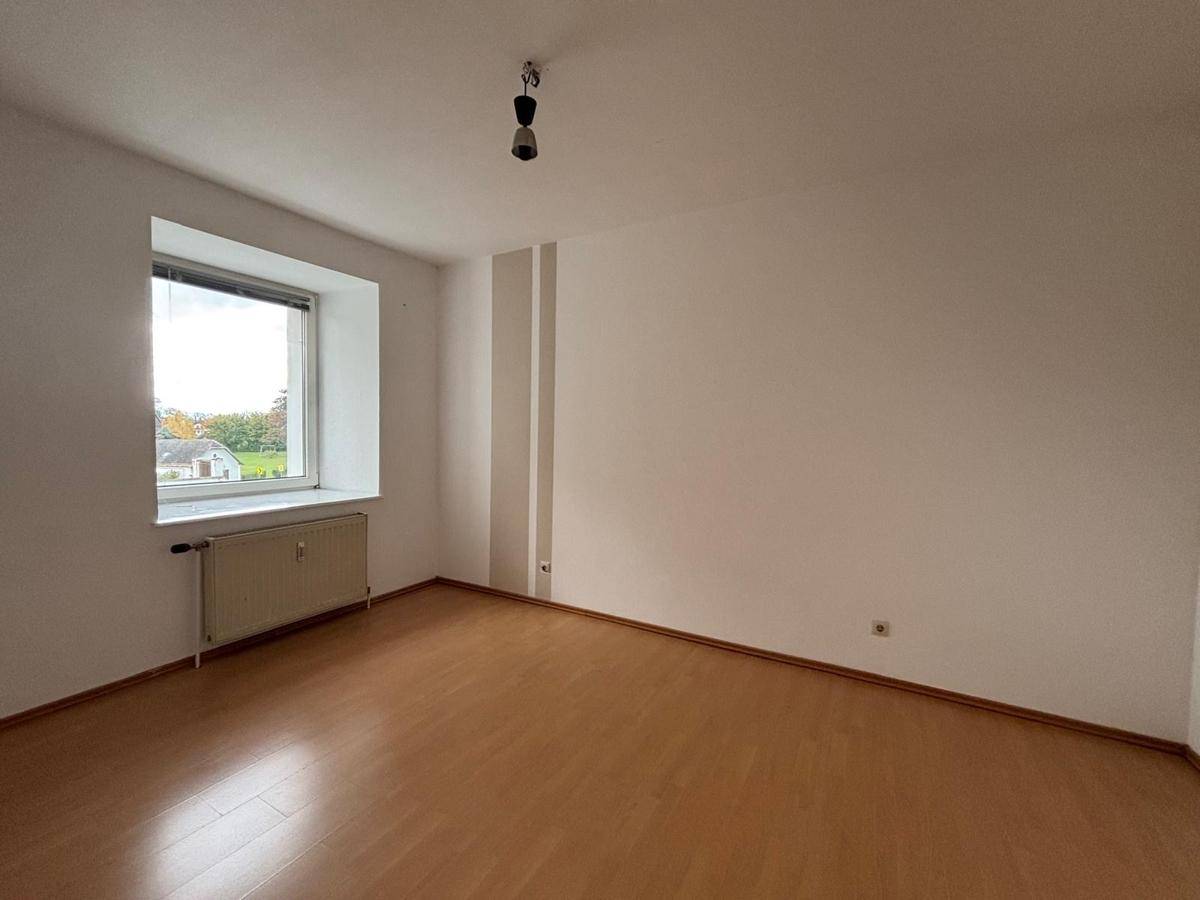 Helles Zimmer mit einem Fenster, Heizkörper und Laminatboden, bietet vielseitige Nutzungsmöglichkeiten.