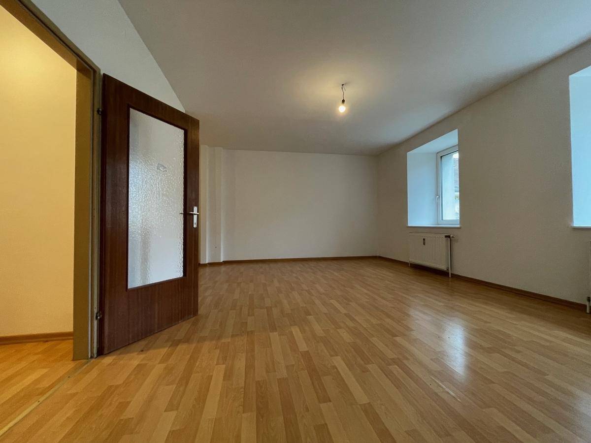 Geräumiges Zimmer mit hellem Parkettboden und einem Fenster, das viel Tageslicht hereinlässt.