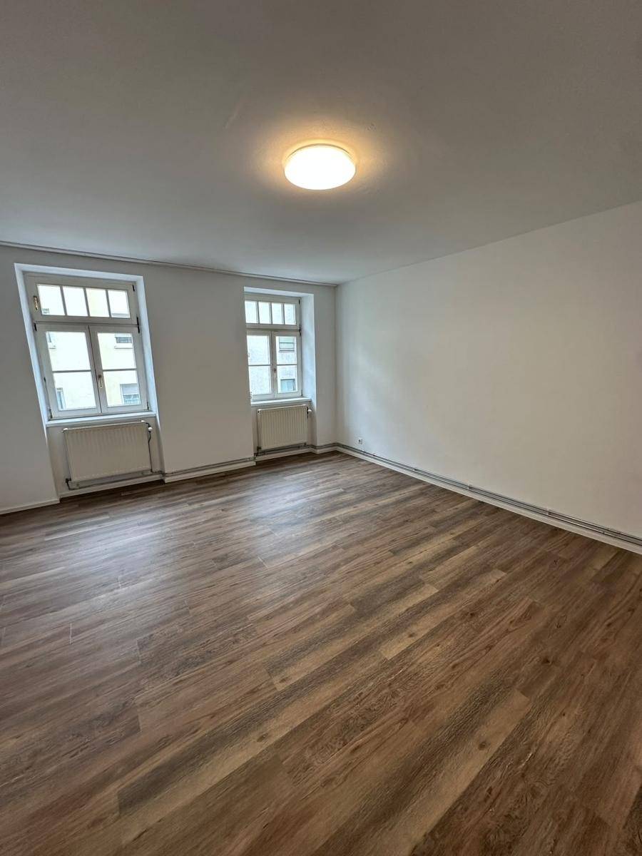 Geräumiges Zimmer mit neuem Laminatboden und weißen Wänden, bereit zur Einrichtung.