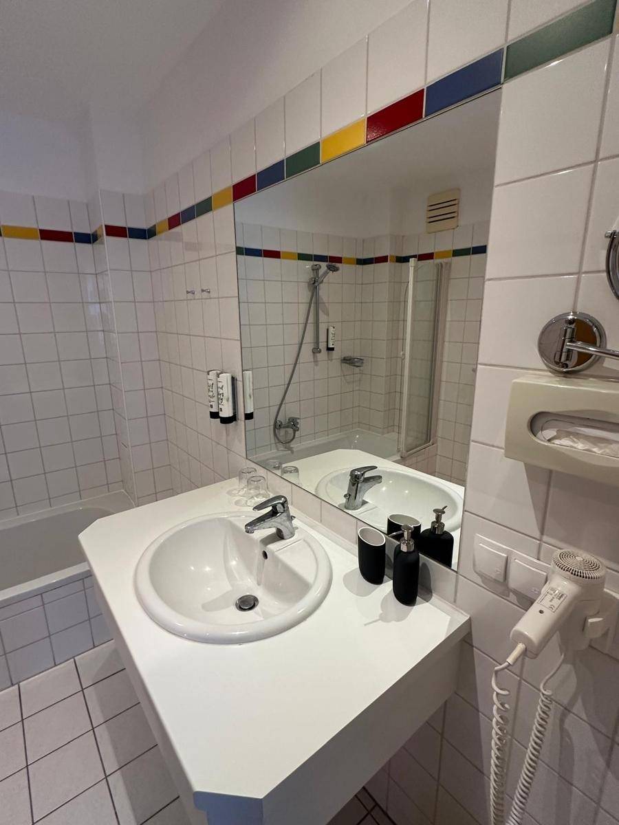 Badezimmer mit Badewanne, Duschbereich, Waschbecken und großem Spiegel über dem Waschtisch.