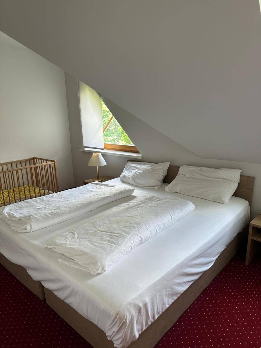 Schlafzimmer im Dachgeschoss mit Doppelbett, Kinderbett und charakteristischen schrägen Wänden.