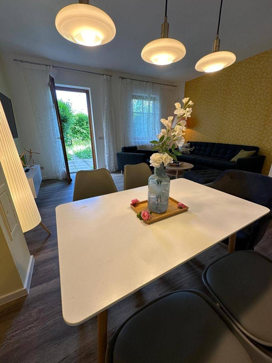 Essbereich mit modernem Tisch und Stühlen, Pendelleuchten und Blick zum Wohnzimmer und Garten.