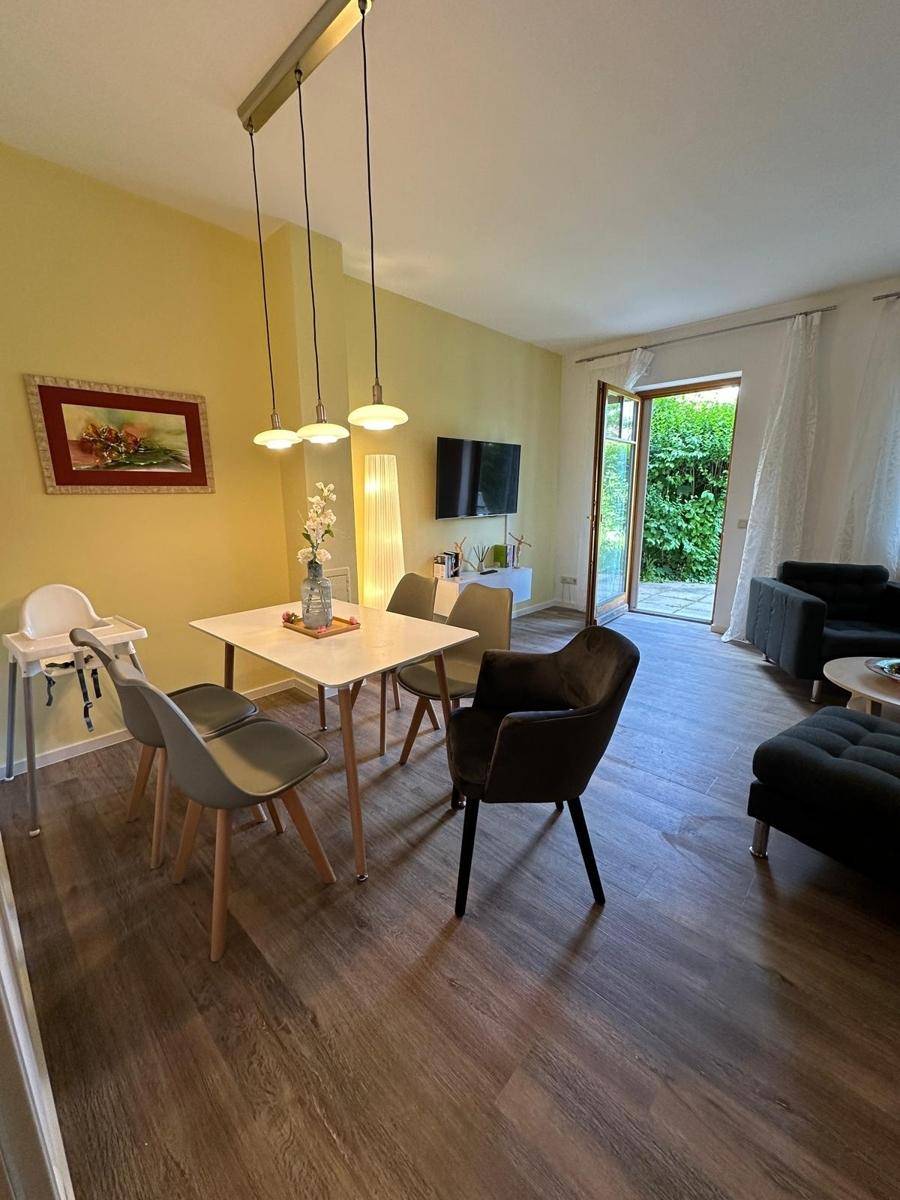 Geräumiger Wohn-Essbereich mit Laminatboden, direktem Zugang zum Garten und moderner Einrichtung.