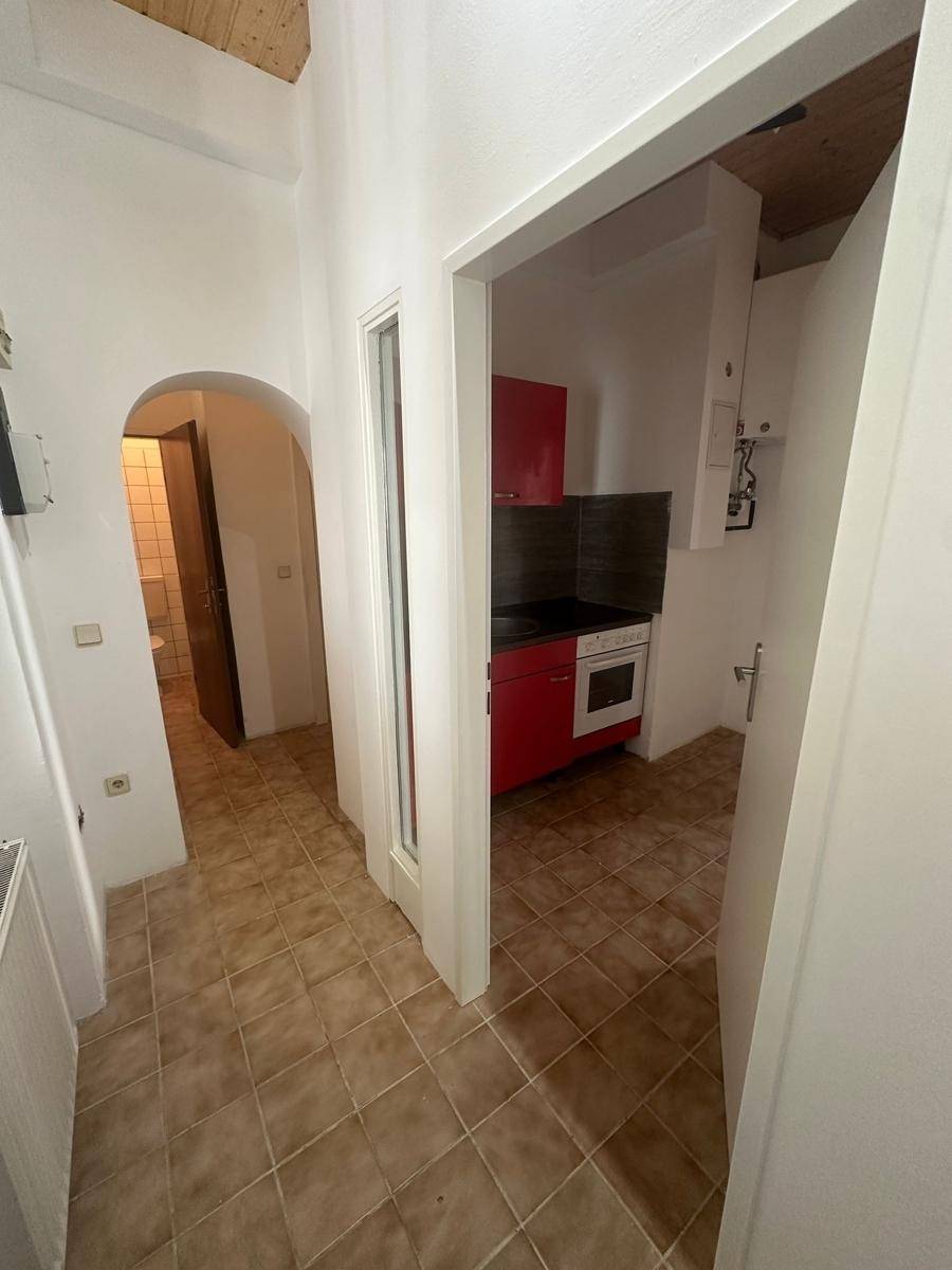 Gefliester Flur mit Zugang zu einer kleinen Küche und einem Badezimmer.