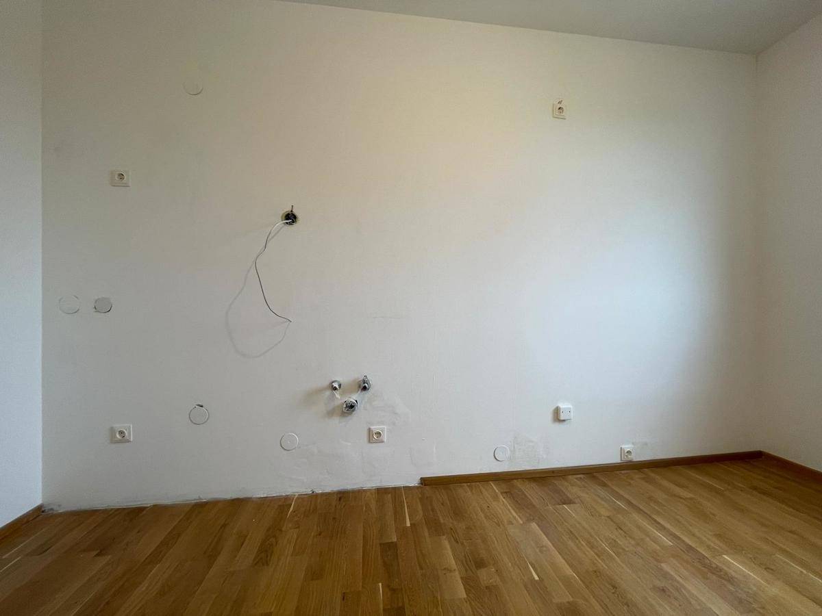 Leeres Zimmer mit Parkettboden und Wandanschlüssen, bereit für die weitere Gestaltung und Einrichtung.